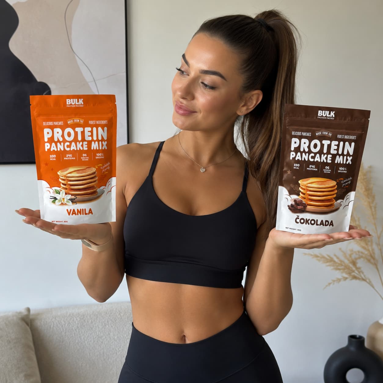 Devojka drzi dve kesice protein pancake mixa od cokolade i vanile